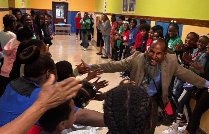  principal with big smile high-fiving students lining hallway